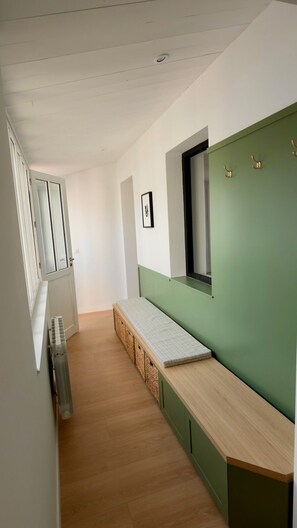 A narrow hallway with a bench, a radiator, and a green wall with a window. - Maison Vicoli, completely new & renovated, Les Portes en Ré, Île de Ré! (Les Portes-en-Ré)
