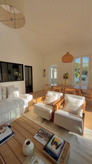 A spacious living area with a large sofa set, a wooden coffee table, and a dining table. - Maison Vicoli, completely new & renovated, Les Portes en Ré, Île de Ré! (Les Portes-en-Ré)