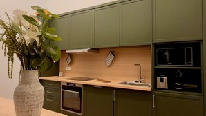 Una cocina moderna con armarios verdes, encimera de madera y un florero con flores.