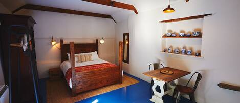 A room with a bed, a table, and shelves with decorative items.