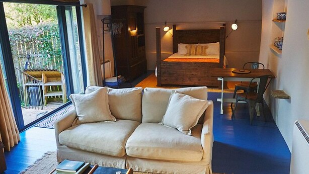 Una camera accogliente con un'ampia finestra, un letto, un divano e un tavolo.