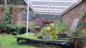 A garden with a raised platform, potted plants, and a brick wall.