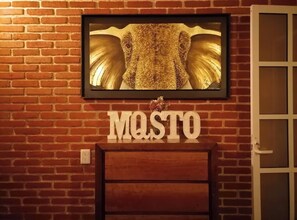 Una obra de arte enmarcada con el rostro de un elefante sobre un muro de ladrillo, con la palabra 'MASTO' debajo.