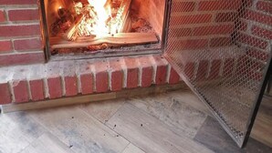A fireplace with a metal screen, a brick wall, and a wooden floor.