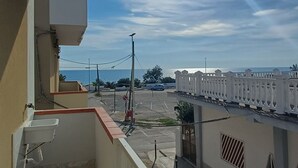 A balcony with a view of the sea and adjacent buildings.