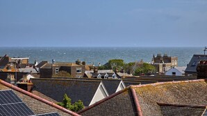 A coastal town with buildings, a view of the sea, and solar panels on rooftops.