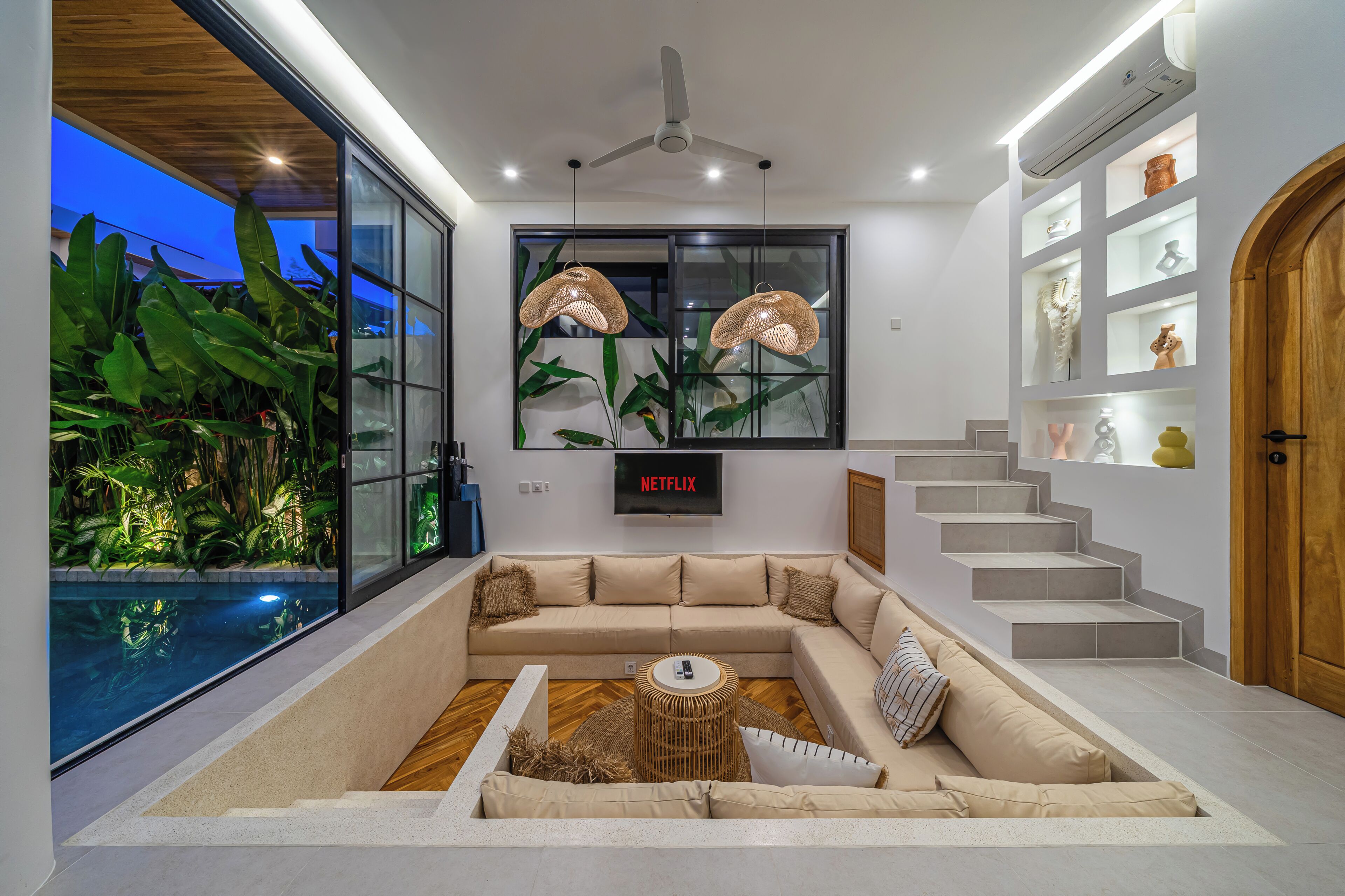 A modern living room with a sofa, a coffee table, a TV, and a staircase.