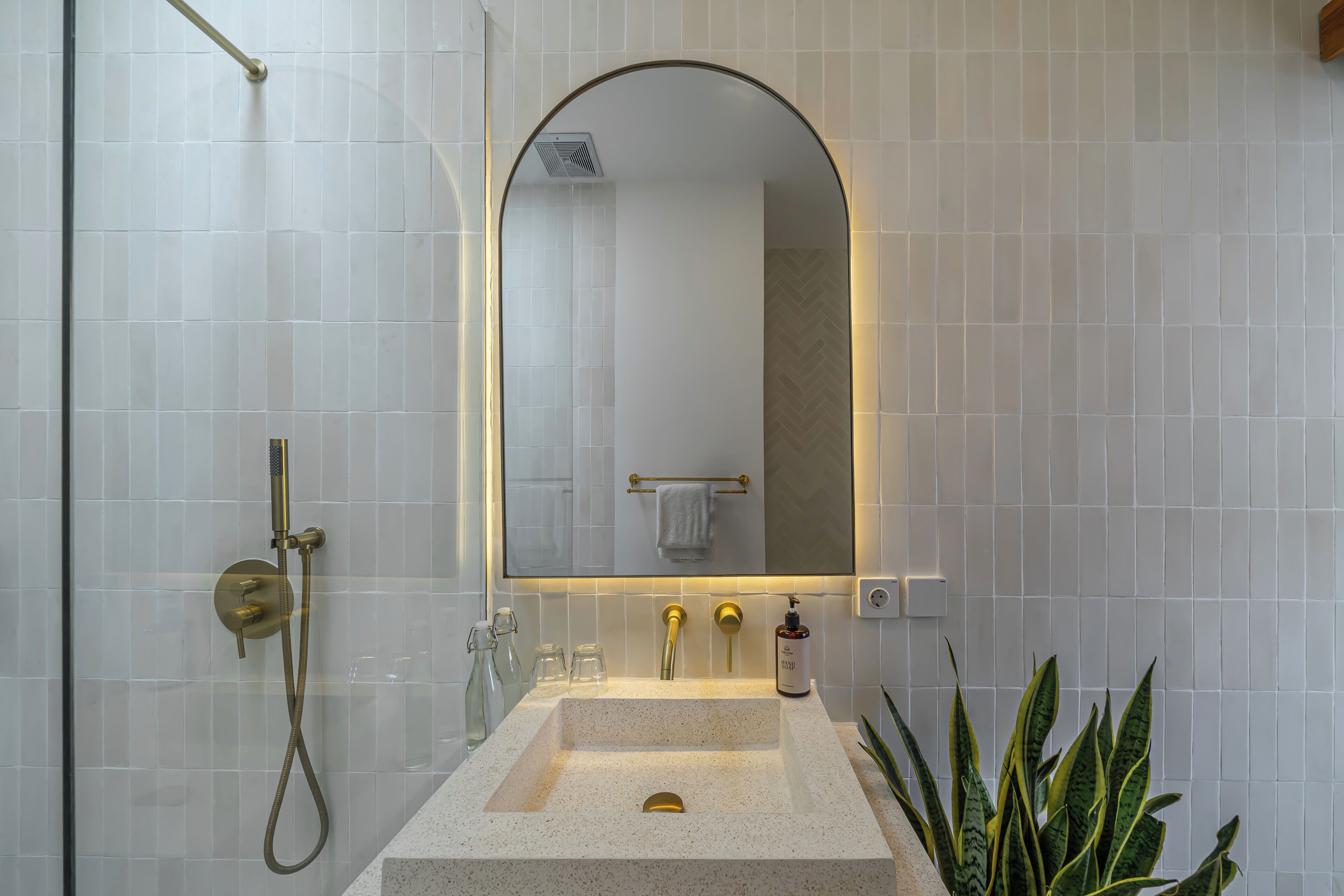 A bathroom with a freestanding sink, a mirror, a towel rack, and a showerhead.