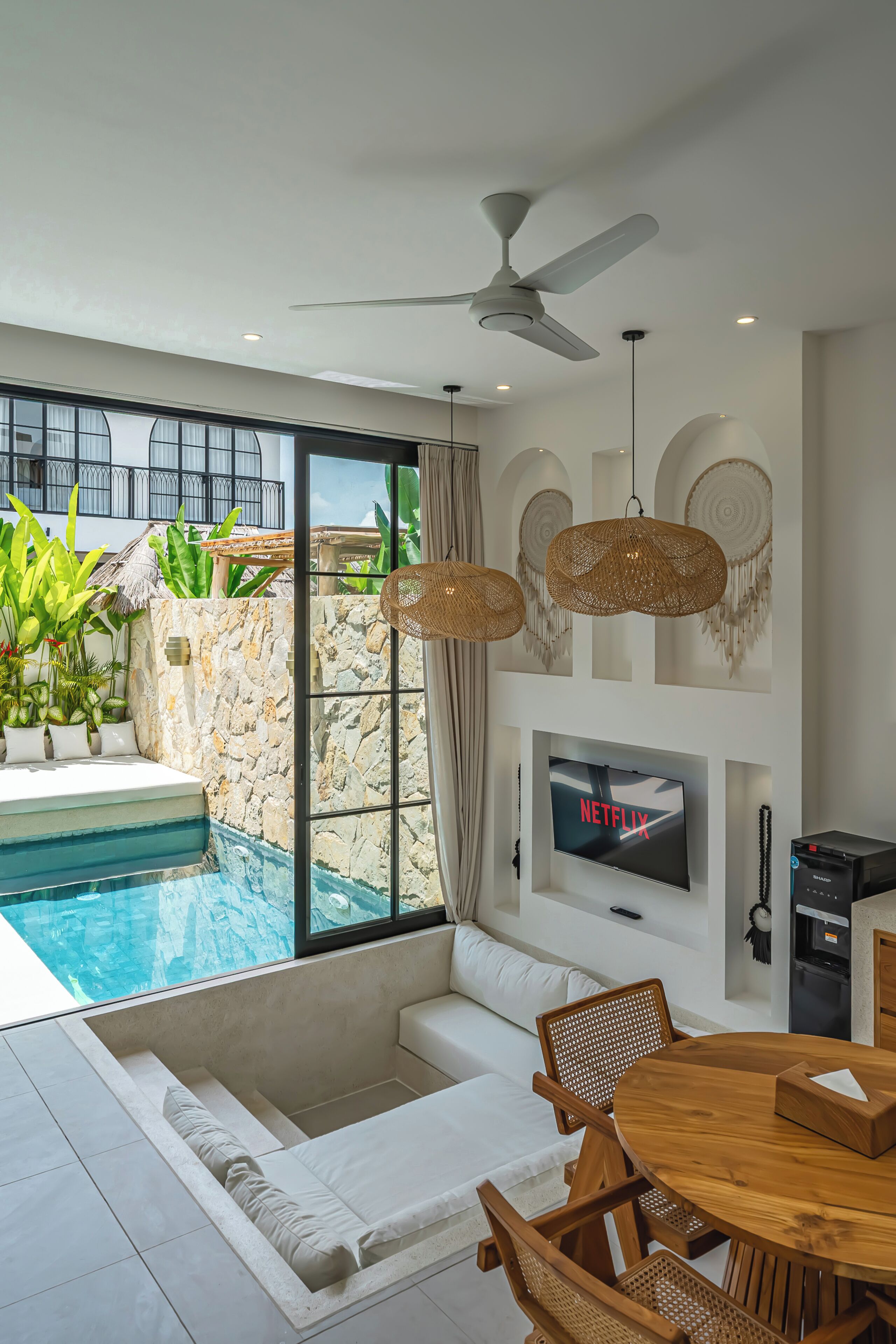 A modern living room with a pool, white furniture, a TV, and a ceiling fan.