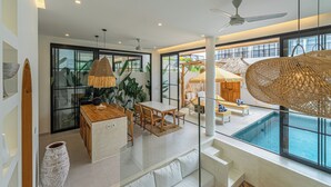 A modern interior with a dining area, a pool, and large windows. - Tropical Mediterranean Villas in Canggu (Canggu)
