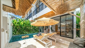 A modern indoor pool area with lounge chairs, a large umbrella, and a view of a lush green wall. - Tropical Mediterranean Villas in Canggu (Canggu)