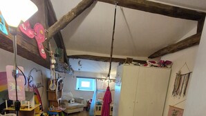 A room with a wooden floor, a white fluffy rug, a hanging red garment, and a white wardrobe. - Family home (Semussac)