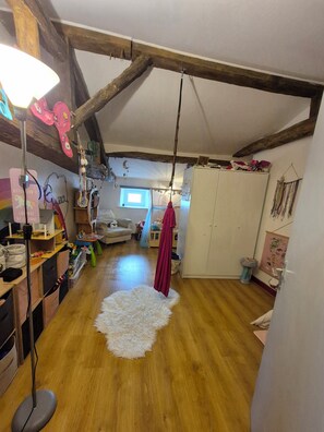 Ein Zimmer mit Holzboden, einem weißen, flauschigen Teppich, einem hängenden roten Kleidungsstück und einem weißen Kleiderschrank.