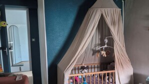 A room with a wooden crib, a small round rug, and a starry wall decoration. - Family home (Semussac)