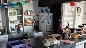 A kitchen with a central island, a refrigerator, and various kitchen items. - Family home (Semussac)