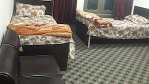 Habitación con dos camas, un sofá y una ventana con cortinas.