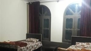 Una habitación con dos camas, un sofá, una mesita y una ventana con cortinas.