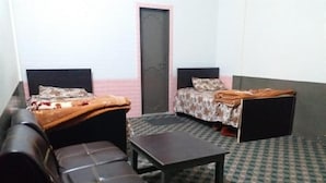 Una habitación con dos camas, un sofá, una mesa y piso estampado.