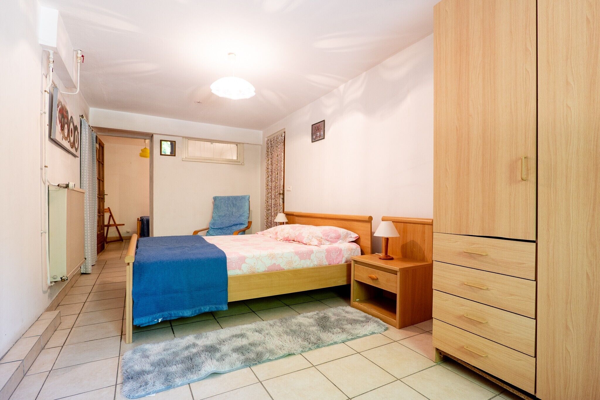 Ein Schlafzimmer mit Bett, Kleiderschrank, Nachttisch und Stuhl.