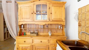 Une cuisine en bois avec un évier, des placards et une fenêtre avec un rideau.
