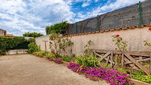 Ein Garten mit Kiesweg, einer mit Kletterpflanzen bewachsenen Mauer und einem Holzzaun.