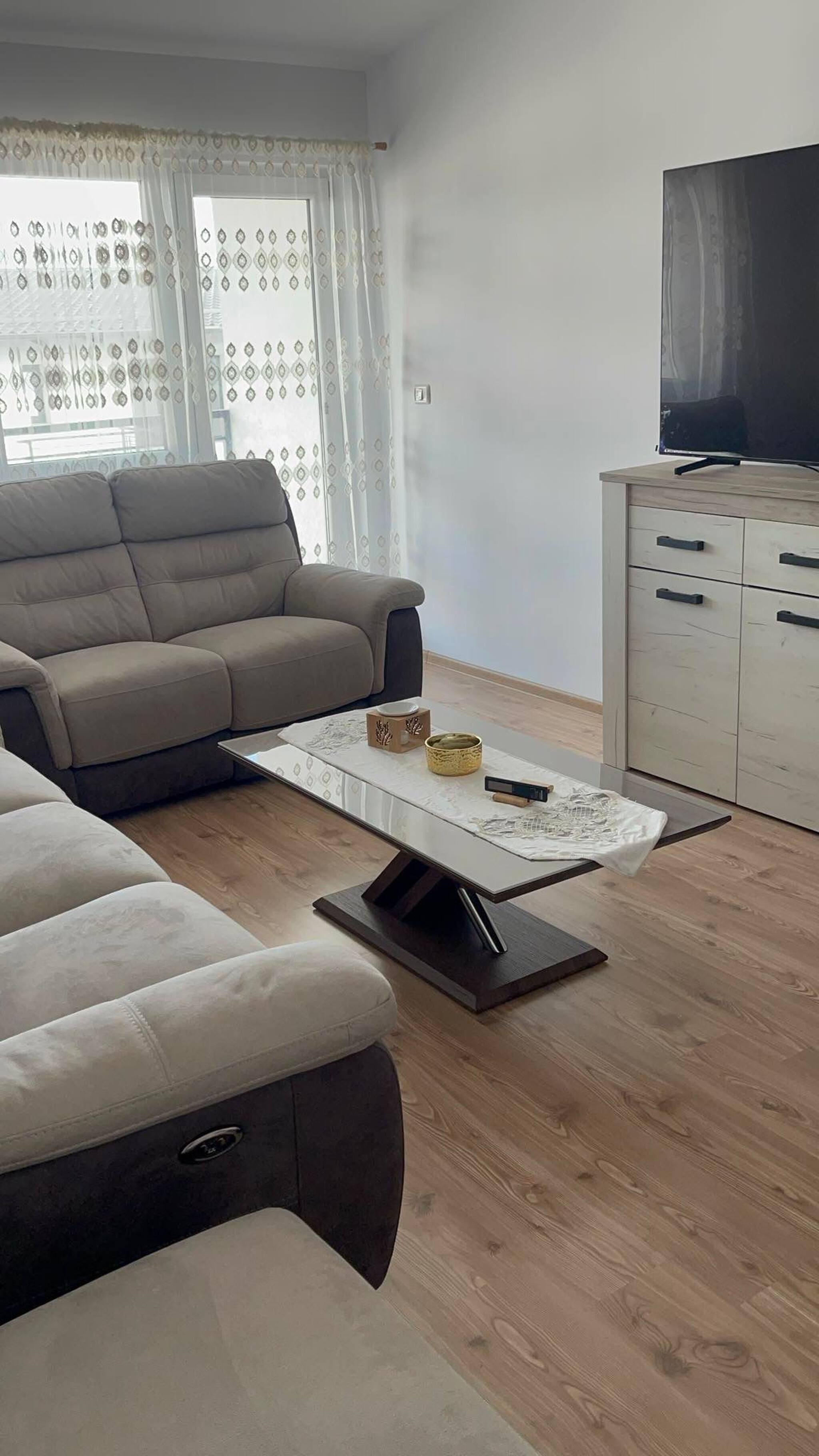 A modern living room with a sofa, a coffee table, and a TV.