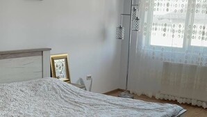 Makuuhuone, jossa on sänky, yöpöytä, lamppu ja ikkuna, jossa on verhot.