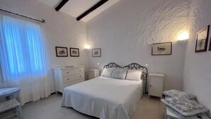 A bedroom with a bed, bedside tables, a chair, and a nightstand. - Beachfront villa with direct beach access - Costa Smeralda (Arzachena)