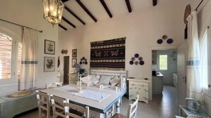 A spacious room with a dining table, chairs, a bed, and a kitchen area. - Beachfront villa with direct beach access - Costa Smeralda (Arzachena)