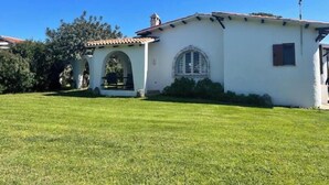 A white building with a tiled roof, a small arched entrance, and a window with a decorative frame. - Beachfront villa with direct beach access - Costa Smeralda (Arzachena)