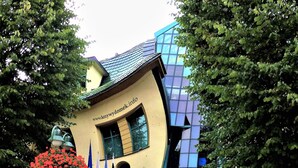 Ein Gebäude mit einem markanten architektonischen Design, mit geneigtem Dach und einer Glasfassade.