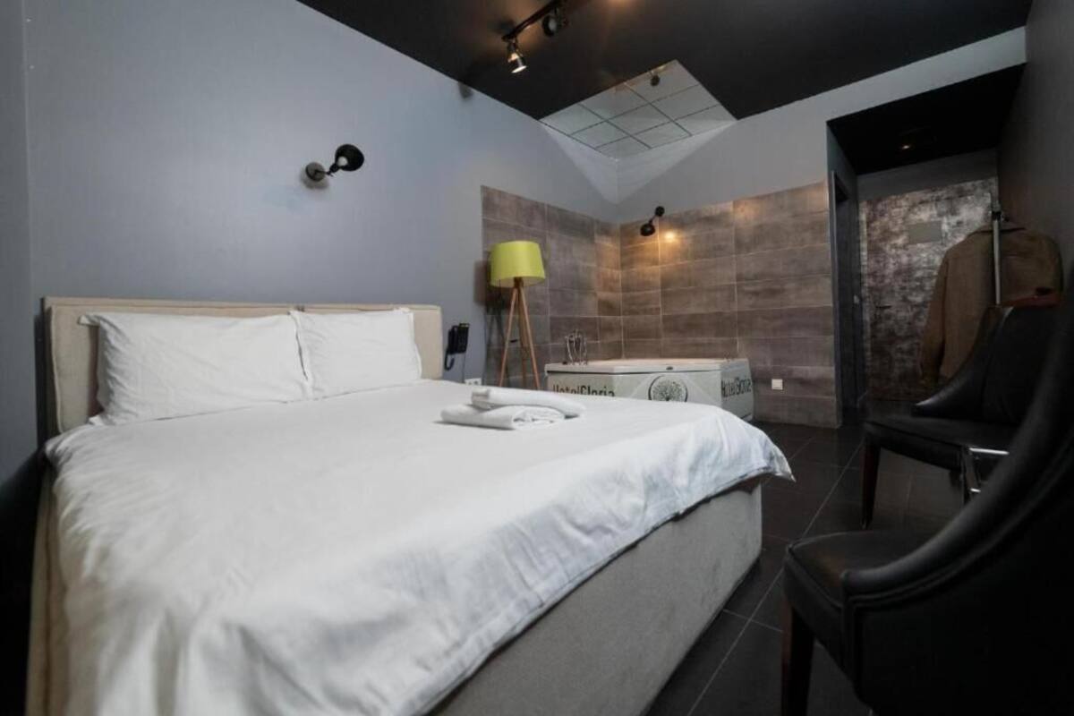 Moderni hotellihuone, jossa on suuri sänky, kylpyammeella varustettu kylpyhuone ja tuoli.
