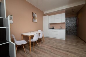 A modern kitchen with white cabinets and a dining area with a table and chairs. - Hotel Gloria KS (Pristina)