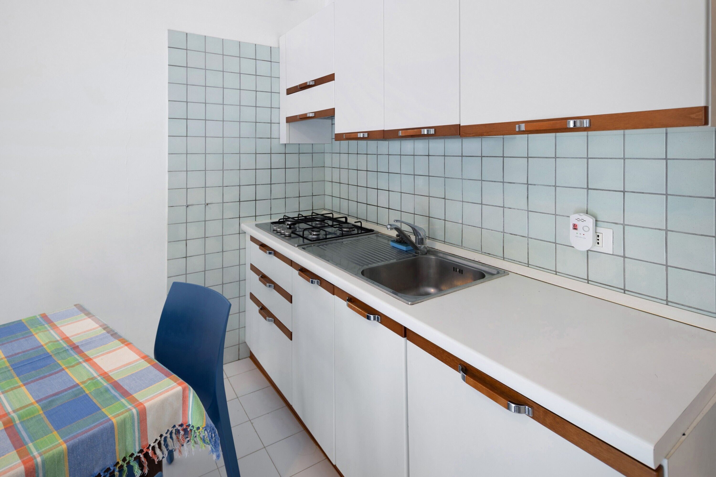 A compact kitchen with a gas stove, sink, and white cabinets.