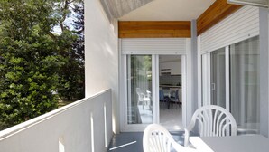 Un balcon avec une table et une chaise blanches, un plafond en bois et une vue sur un jardin.