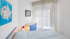 Une chambre à coucher avec un lit, une commode, une carte accrochée au mur et une fenêtre avec des rideaux.