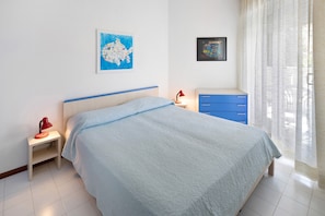 Une chambre à coucher avec un lit, une table de chevet avec une lampe, une commode et deux tableaux encadrés accrochés au mur.