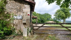 A stone building with a sign reading 'LANTUILERIE PROPRIETE SERVICIE' and a wooden gate leading to a covered outdoor area.