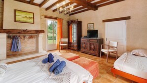 A bedroom with a bed, a television, a wooden cabinet, and a fireplace.