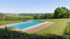 A rectangular swimming pool with a clear blue water surface, surrounded by a gravel area and a grassy lawn.