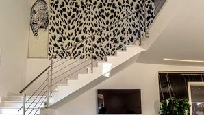 Ein modernes Interieur mit Treppe, Wand mit Leopardenmuster, grünem Sofa und Flachbildfernseher.