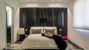 Ein modernes Schlafzimmer mit einem großen Bett, einem Nachttisch, einer Lampe und einem roten Hocker.