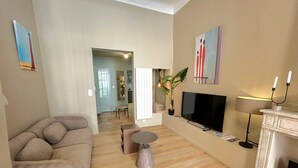 Una sala de estar con sofá, televisión, chimenea y obras de arte en las paredes.
