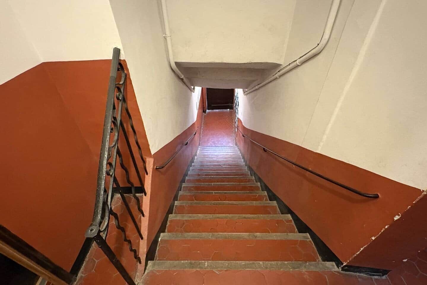 En trappe med gelænder, der fører op til en platform med en lampe.