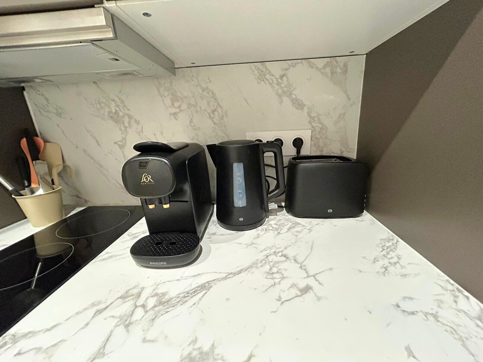 A kitchen with a coffee maker, toaster, and a mug on a marble countertop.