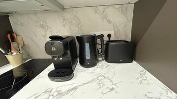 A kitchen with a coffee maker, toaster, and a mug on a marble countertop.