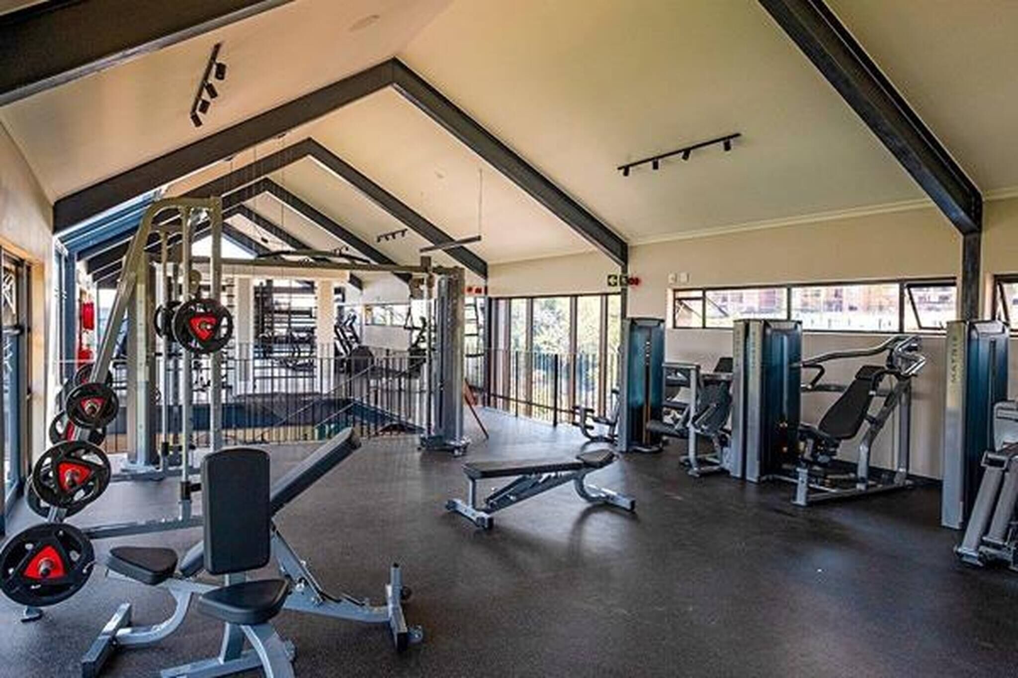 A gym with weightlifting equipment, benches, and cardio machines.