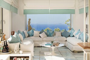 Ein Wohnzimmer mit großem Fenster, einer Couch, einem Couchtisch und Dekorationselementen.