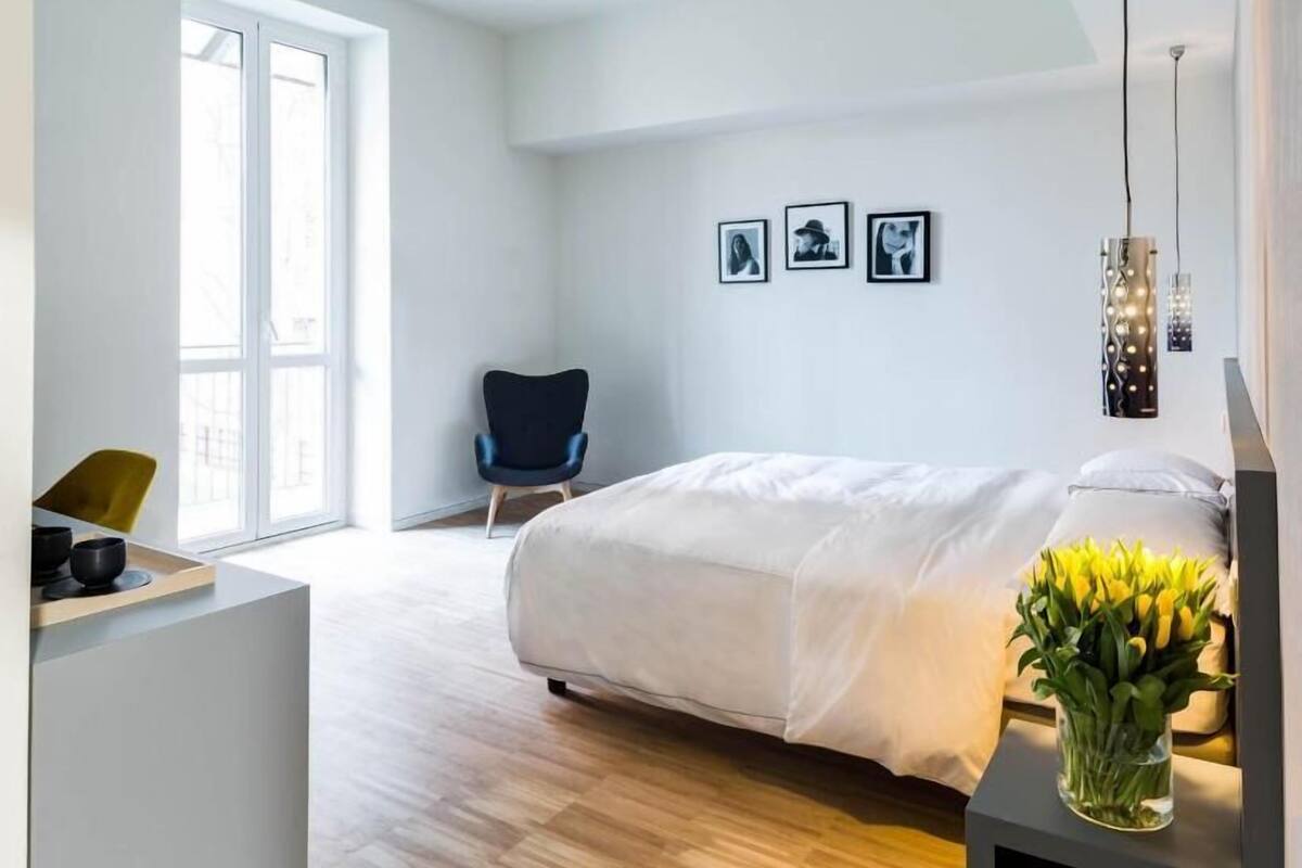 A modern bedroom with a bed, a desk, a chair, and a window.