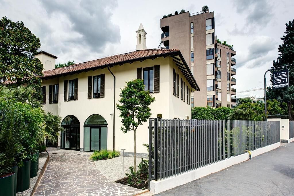A two-story building with a tiled roof, a gated entrance, and a paved pathway leading to the door.
